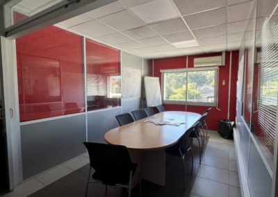 Salle de réunion transformée en bureau de direction avec baie vitrée et vitrophanie